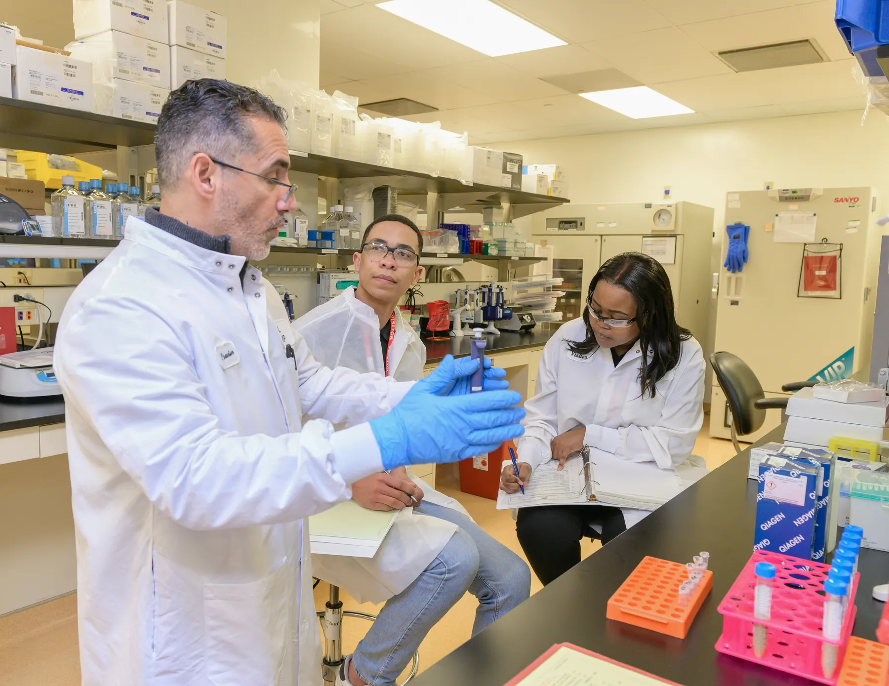Students and a scientist working at a lab bench