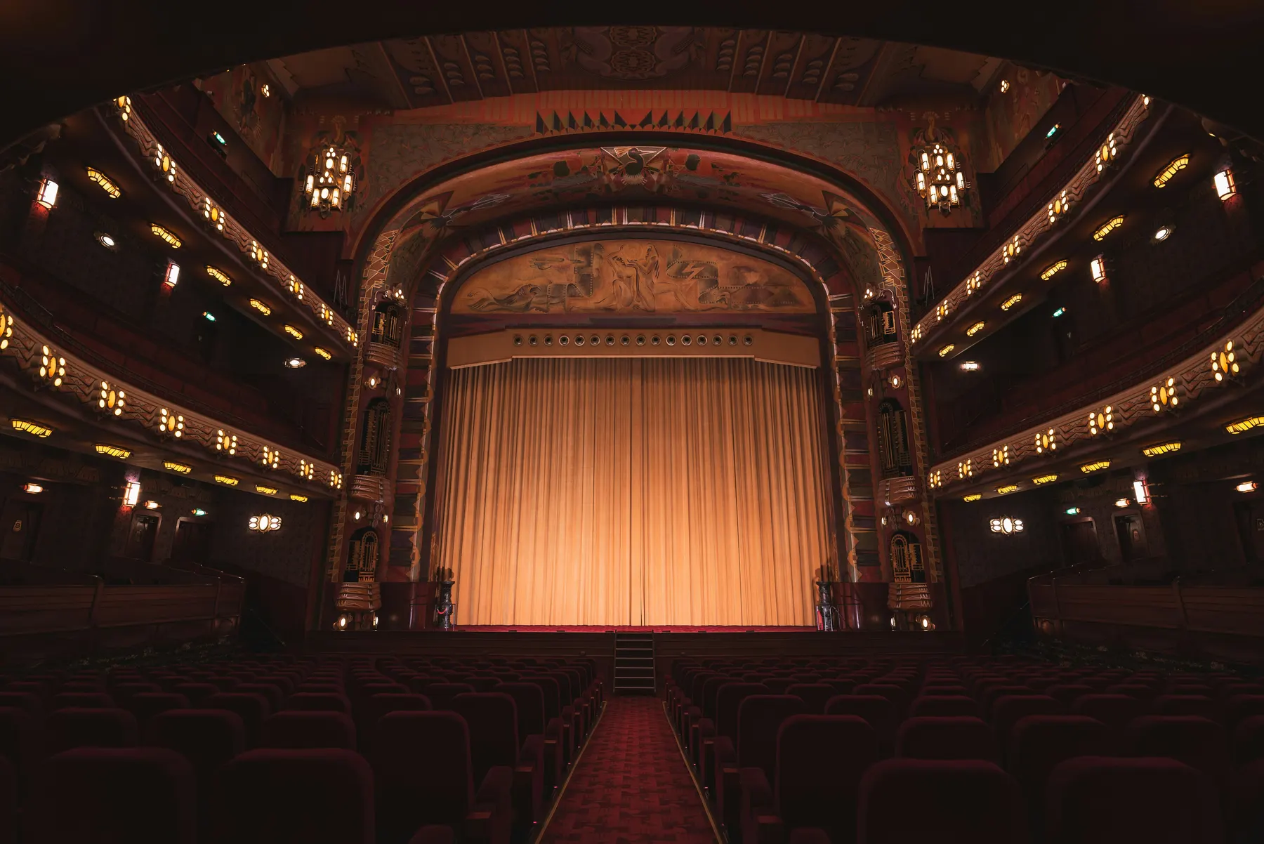 An empty theater with a lit stage curtain