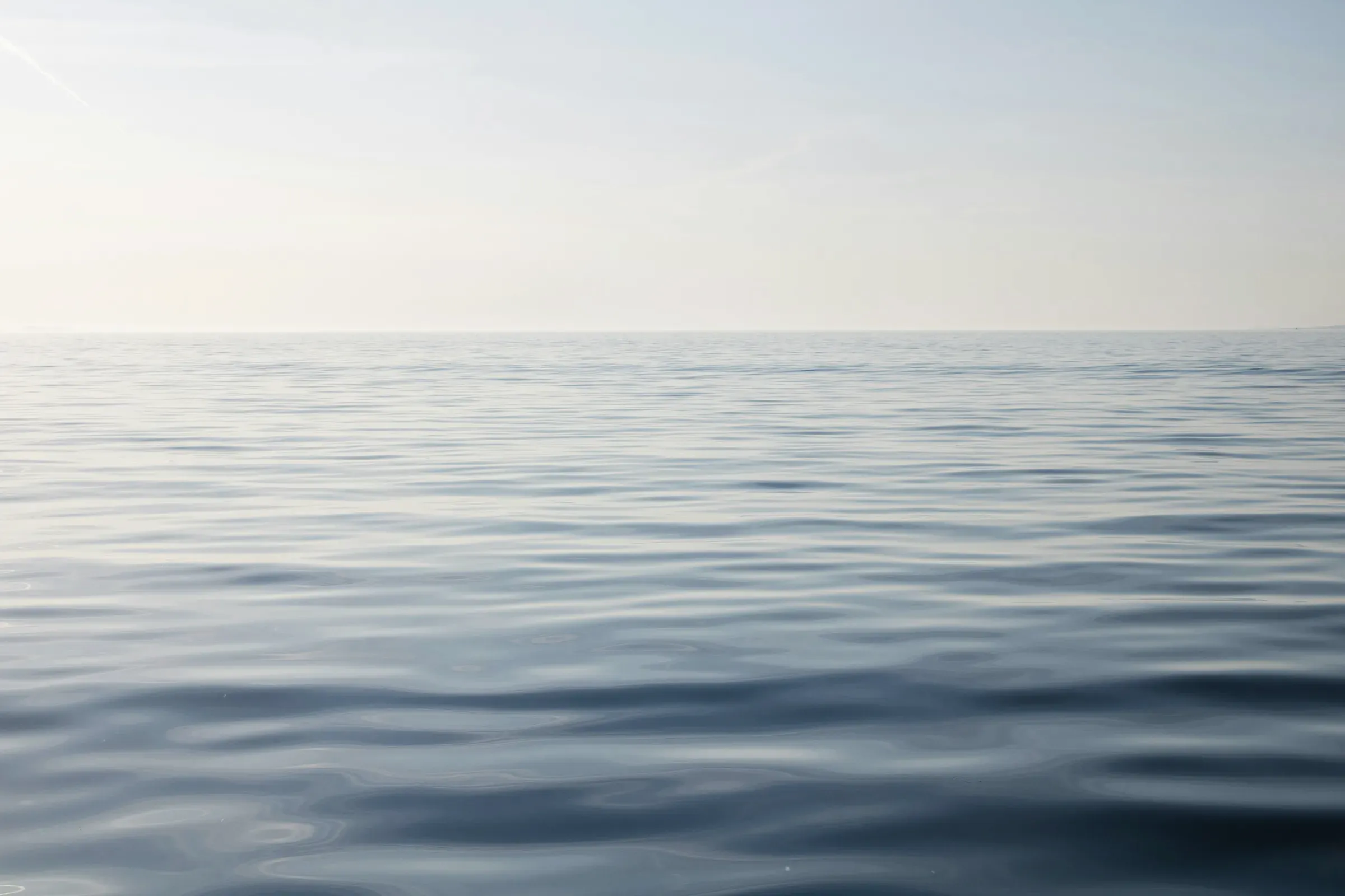 Flat, dark water under a pale sky before sunrise