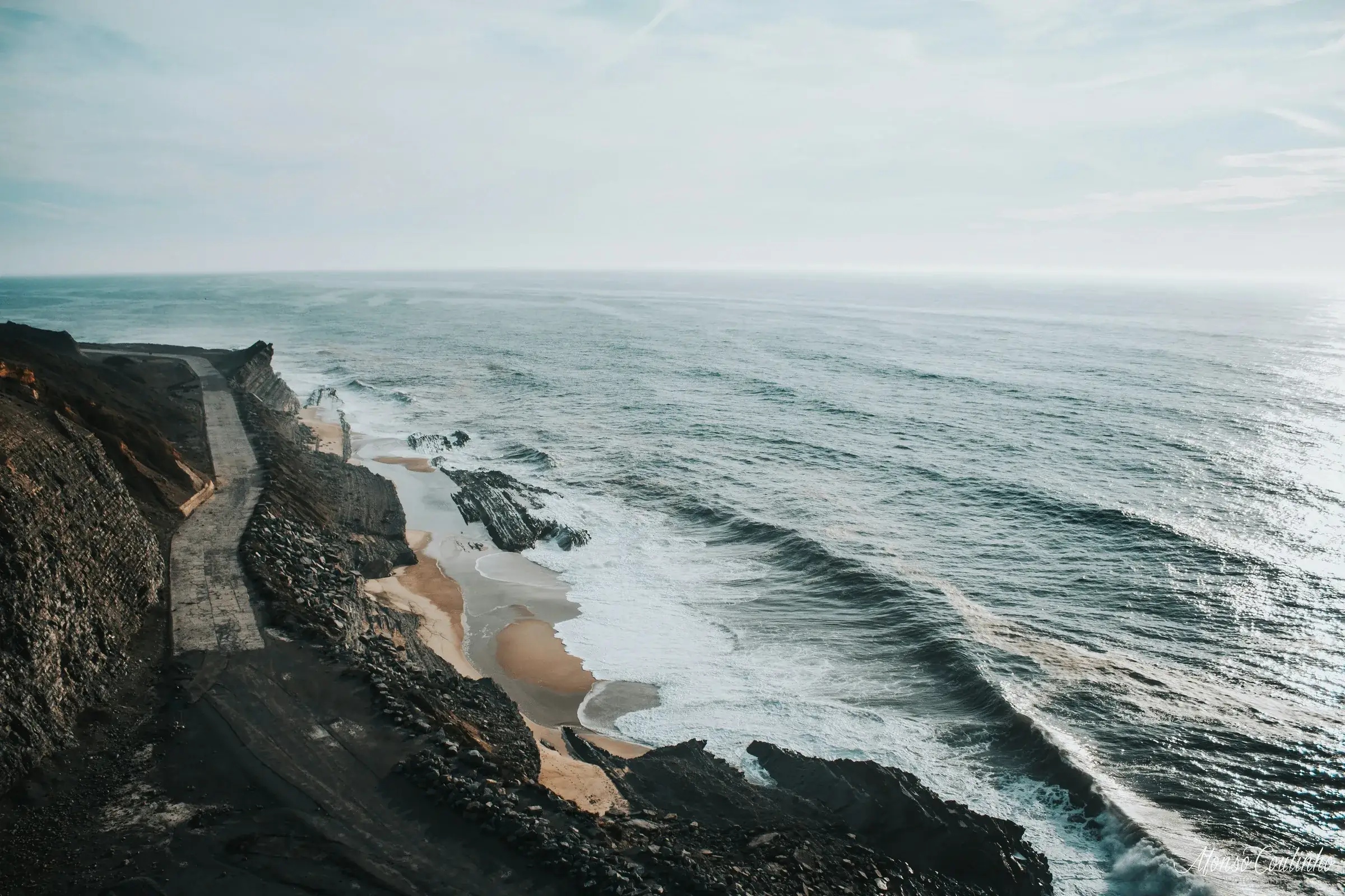 A dark cliff edge above white water on the headland path