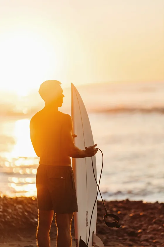 Portrait of a guide on the beach at sunset holding a board